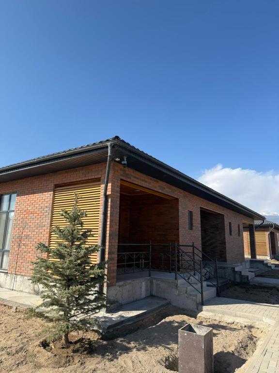 a building with two garage doors and a tree at Коттедж Alfa in Koshkolʼ