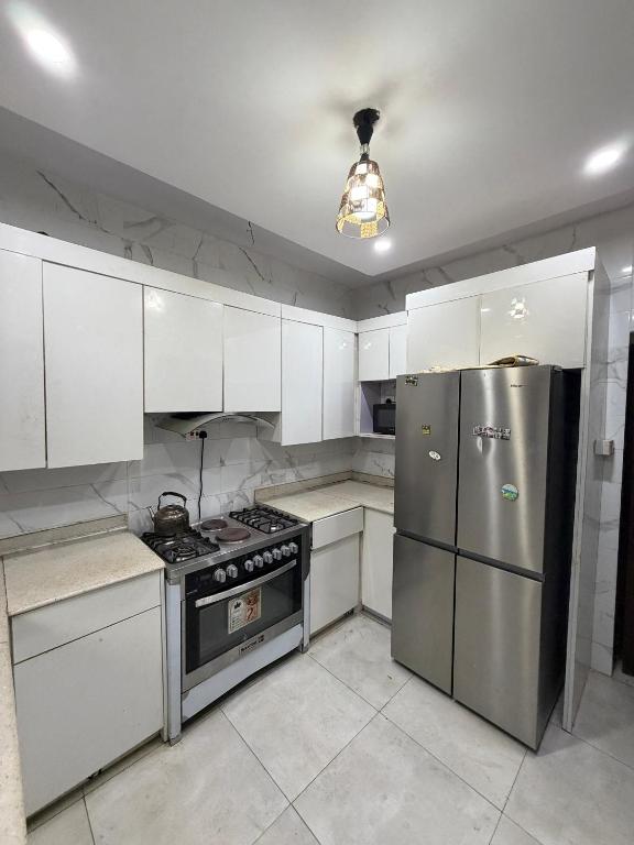 a kitchen with white cabinets and a stainless steel refrigerator at 3 Bedroom Flat Short Let in Iseri