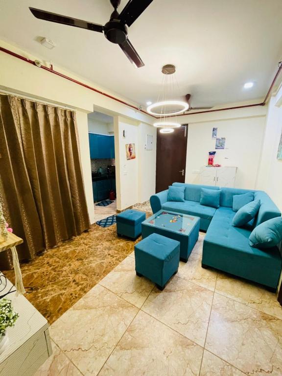 a living room with blue couches and a ceiling fan at AM Living in Ghaziabad