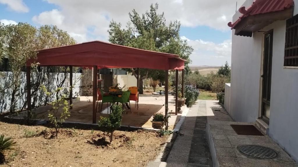 a covered porch of a house with a red canopy at منزل ومزرعه للايجار الشوبكً Farm for rent , Shoubak , Petra in Nijil