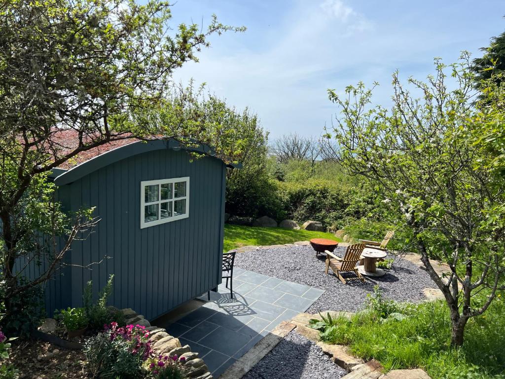 a shed with a table and chairs in a garden at Bluebell Shepherd's Hut in Llanfair
