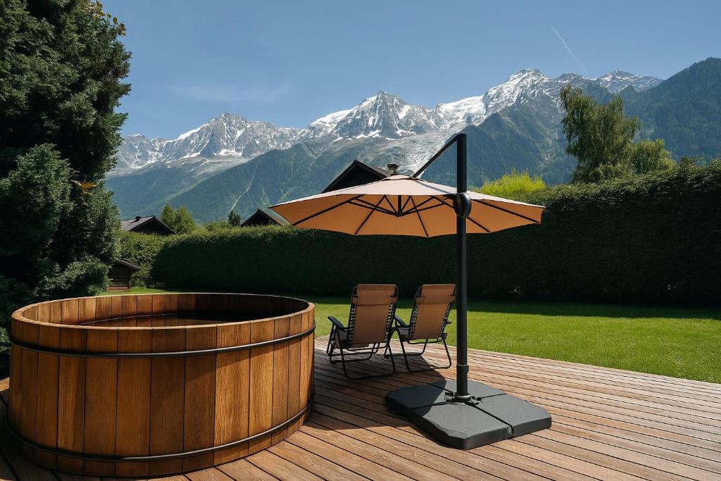 a table and chairs under an umbrella on a deck at Luxurious Chalet With Breathtaking Mont Blanc Massif Views From Hot Tub and Garden plus Sauna in Les Houches