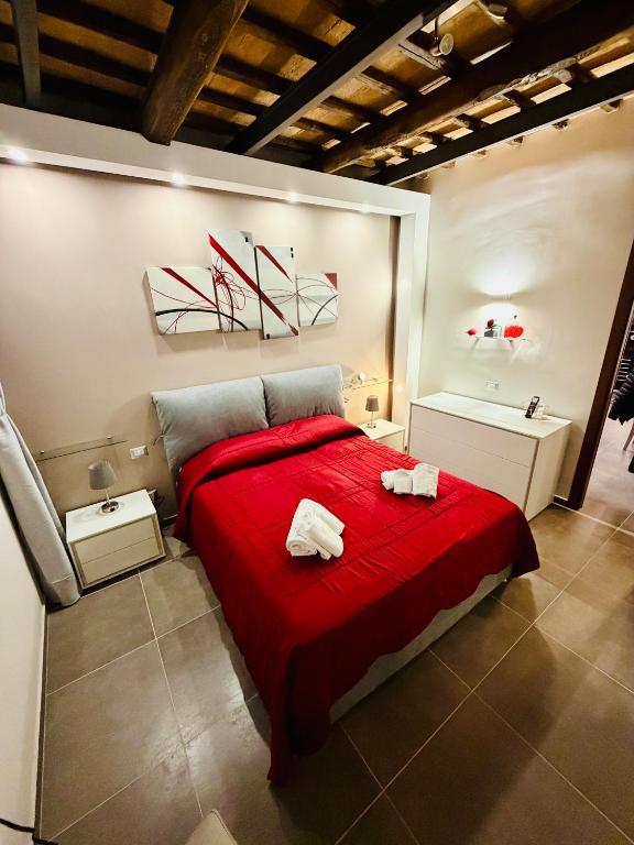 a bedroom with a red bed with two towels on it at Il Nido della Regina - 250m dal Lago di Bolsena in Marta