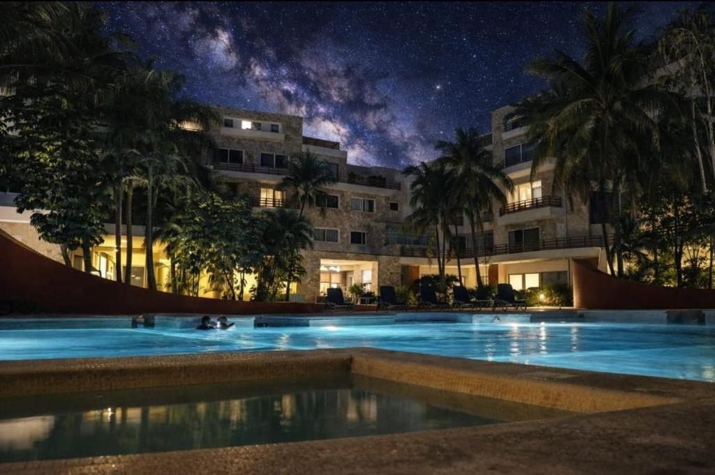 ein großes Schwimmbecken vor einem Gebäude bei Nacht in der Unterkunft Oasis del Sol in Playa del Carmen