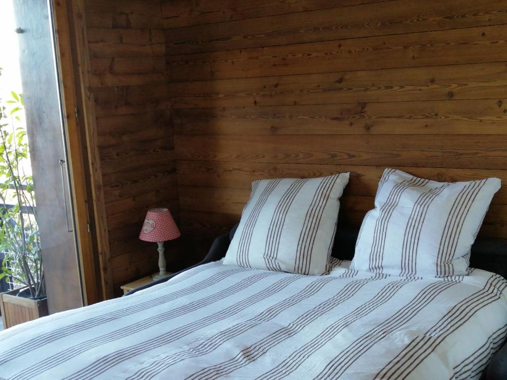 a bedroom with a bed with a wooden wall at Charming mountain studio in Mont-Saxonnex