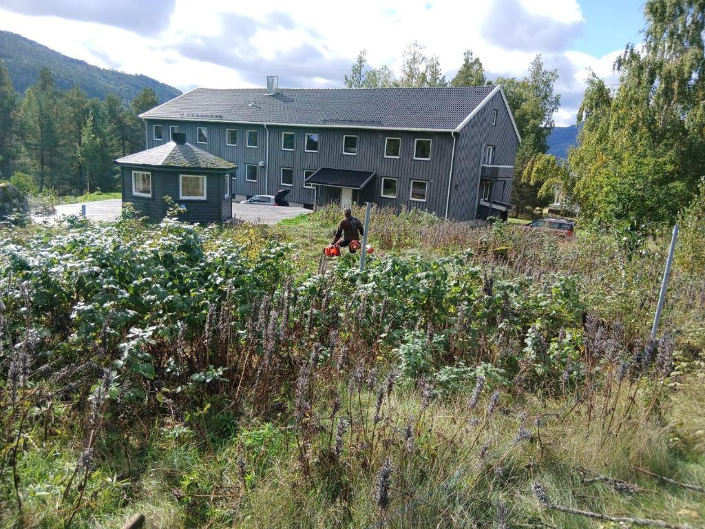 a man standing in a field in front of a building at The Sisters Landeskogen in Grendi