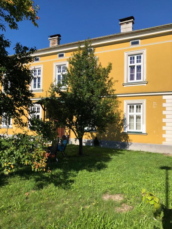 a large yellow building with a tree in the yard at Löwenzahn in Scheibbs