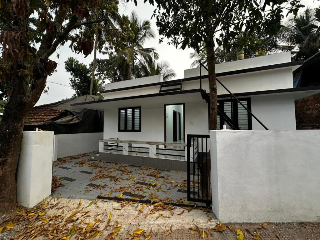 a white house with a fence in front of it at Cozstel in Kozhikode