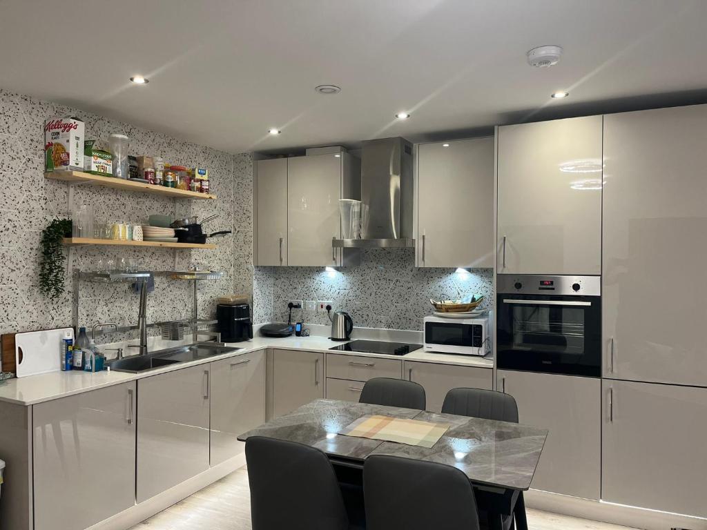 a kitchen with white cabinets and a table with chairs at Host-Free Ensuite Double Bed by Heathrow in Feltham