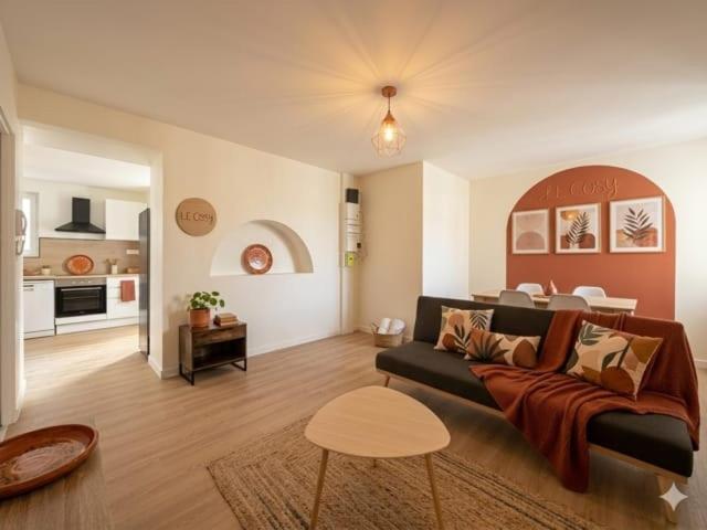 a living room with a couch and a kitchen at 8B - Le Cosy in Saint-Rambert-dʼAlbon