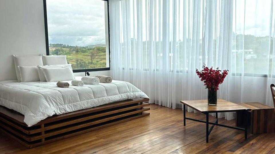 a bedroom with a bed with a table and a large window at Ricefield Valley in Mandrangobato