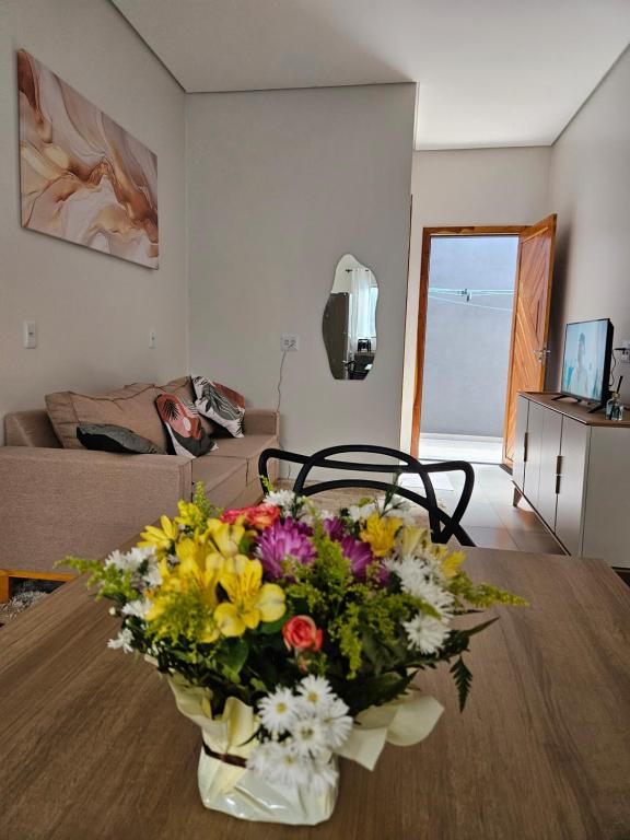 a vase of flowers on a table in a living room at Apartamento completo - a 3 minutos do centro in Alta Floresta