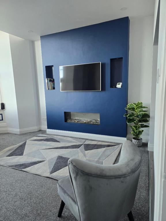 a living room with a chair and a blue wall at Antrim Holiday Apartment in Ramsey