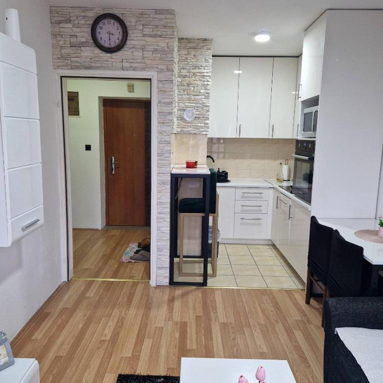 a kitchen with white cabinets and a clock on the wall at Apartman Zivkovic in Bosanska Dubica