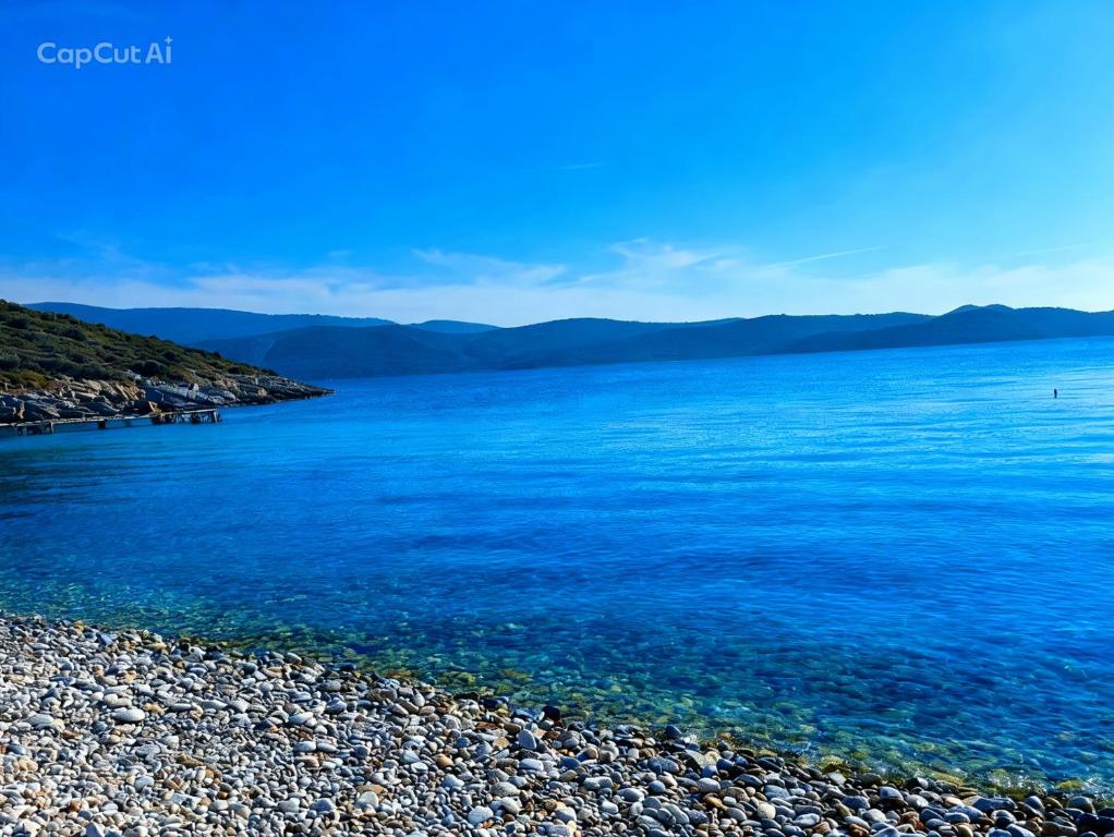 a large body of water with a rocky beach at The simple two-bedroom house at Klima Beach in Samos