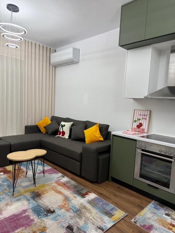 a living room with a black couch and a kitchen at White Apartment in Kamëz