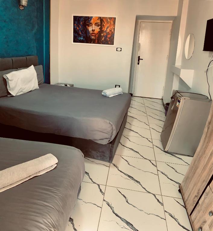 a hotel room with two beds and a tile floor at Nada HOTEL in Cairo