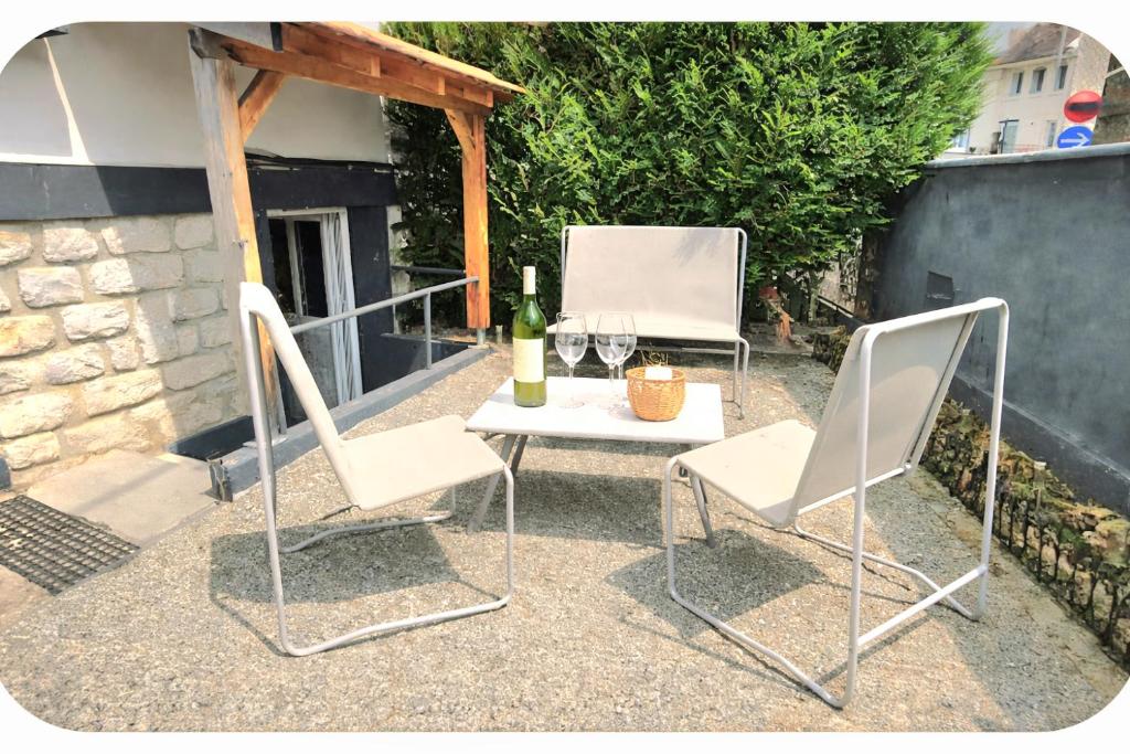 two white chairs and a table with a bottle of wine at Côté cour, T2 espace exterieur au calme in Lourdes