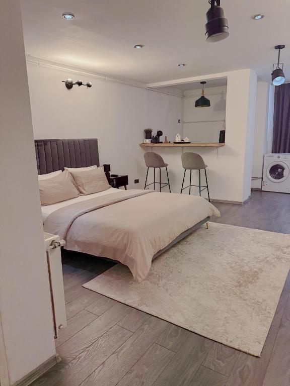 a bedroom with a bed with two chairs and a kitchen at Signature Residence in Mediaş