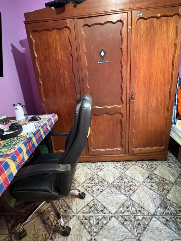 a desk with a chair in front of a cabinet at Quarto com duas camas confortáveis in Belo Horizonte