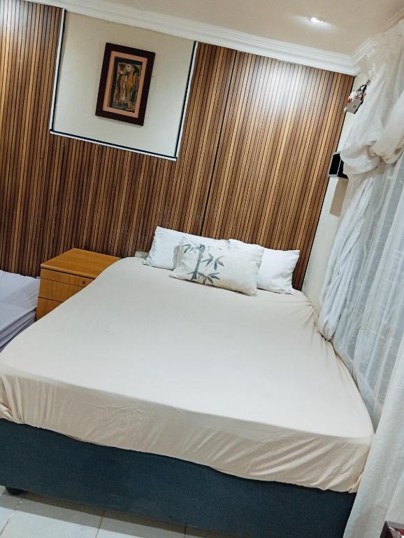 a bedroom with a large white bed with wooden walls at 3 bedroom self catering in Rustenburg
