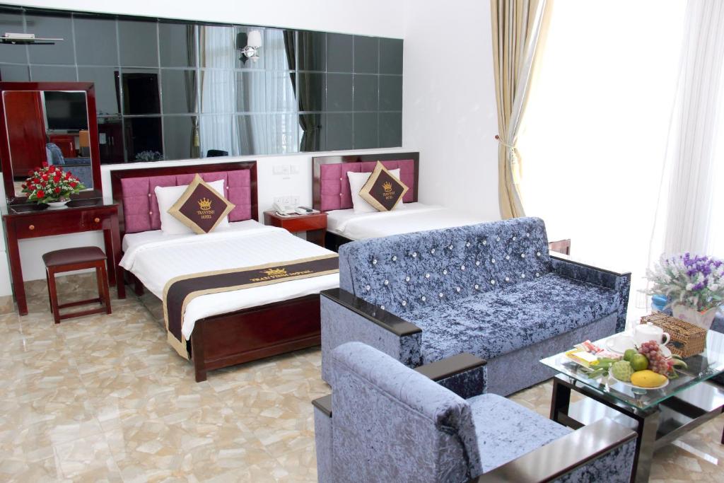 a hotel room with two beds and a couch at Tran Vinh Hotel in Bạc Liêu