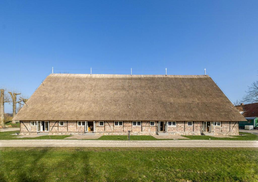 a large stone building with a grass roof at Relax In A Thatched Barn With A Sauna in Ratekau