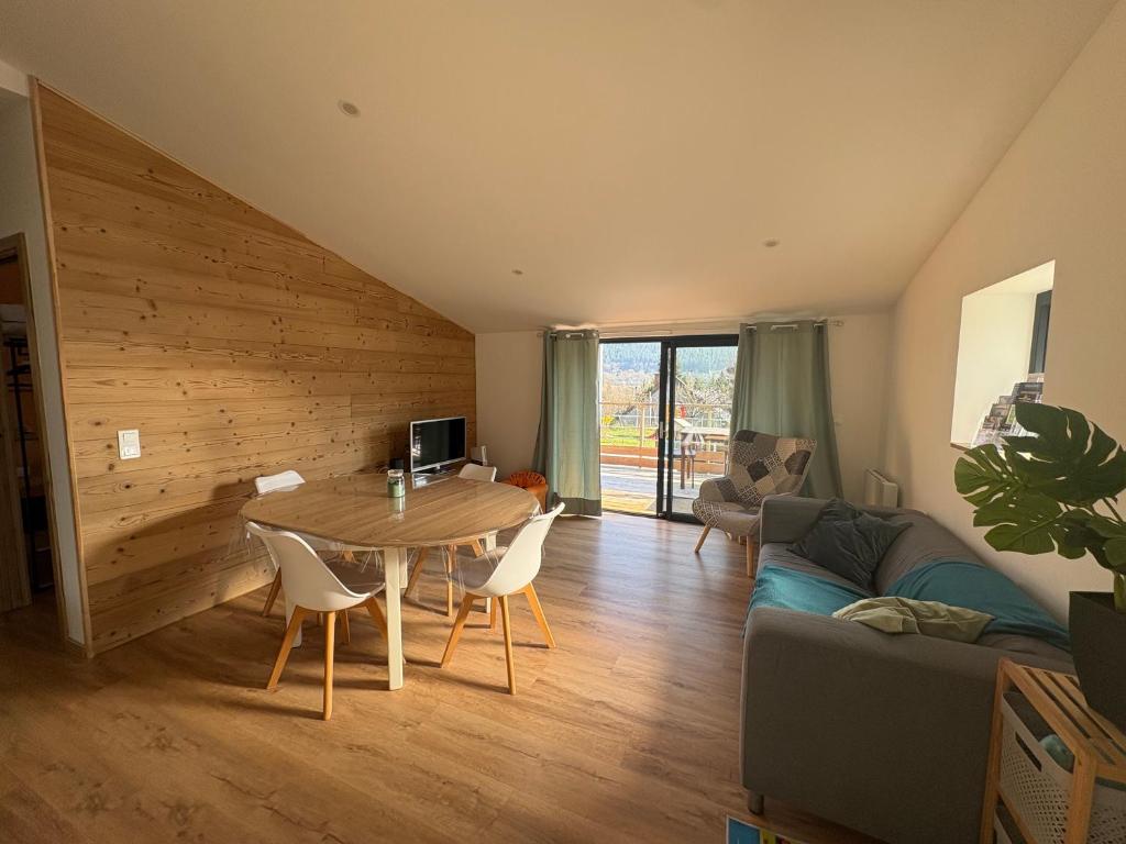 a living room with a table and a couch at Le Chalet des 5 avec piscine vue sur les montagnes et en lisière de forêt in Lutzelhouse