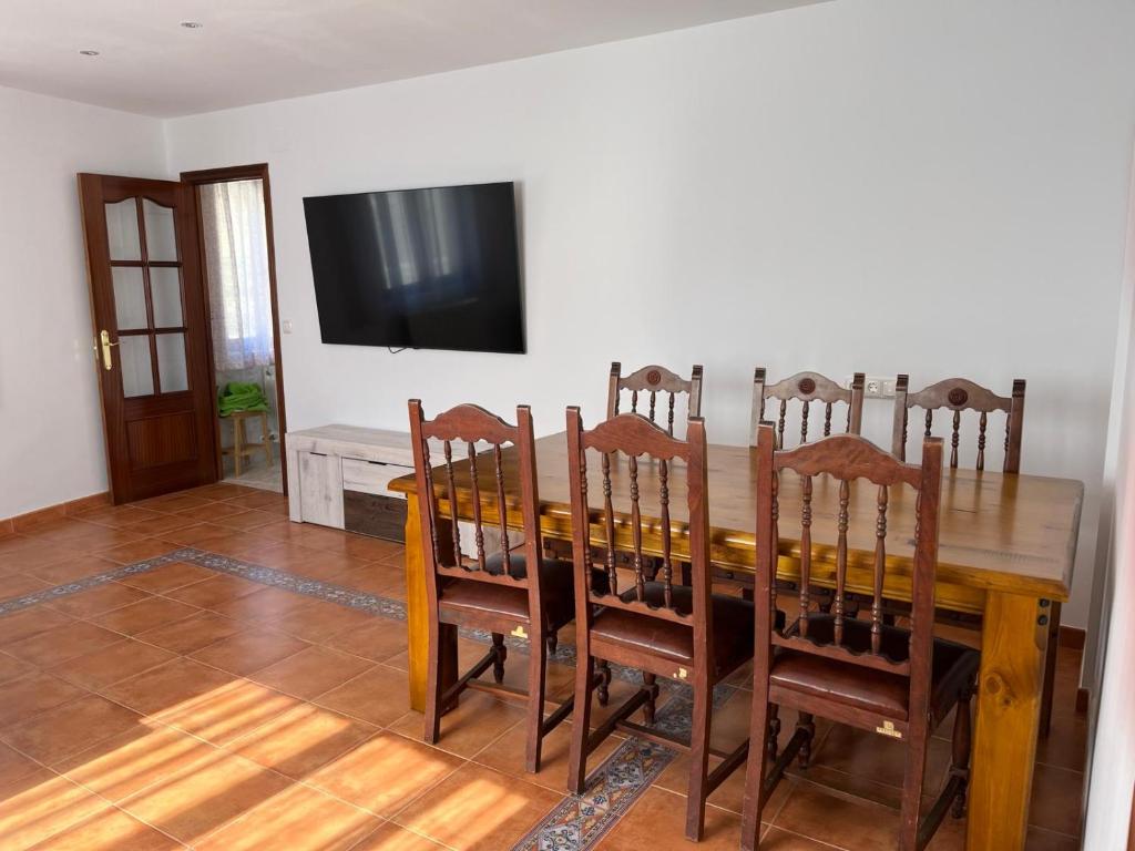 a dining room table with chairs and a television on a wall at Mil Mariposas, Escapada rural Burgos in Barriosuso