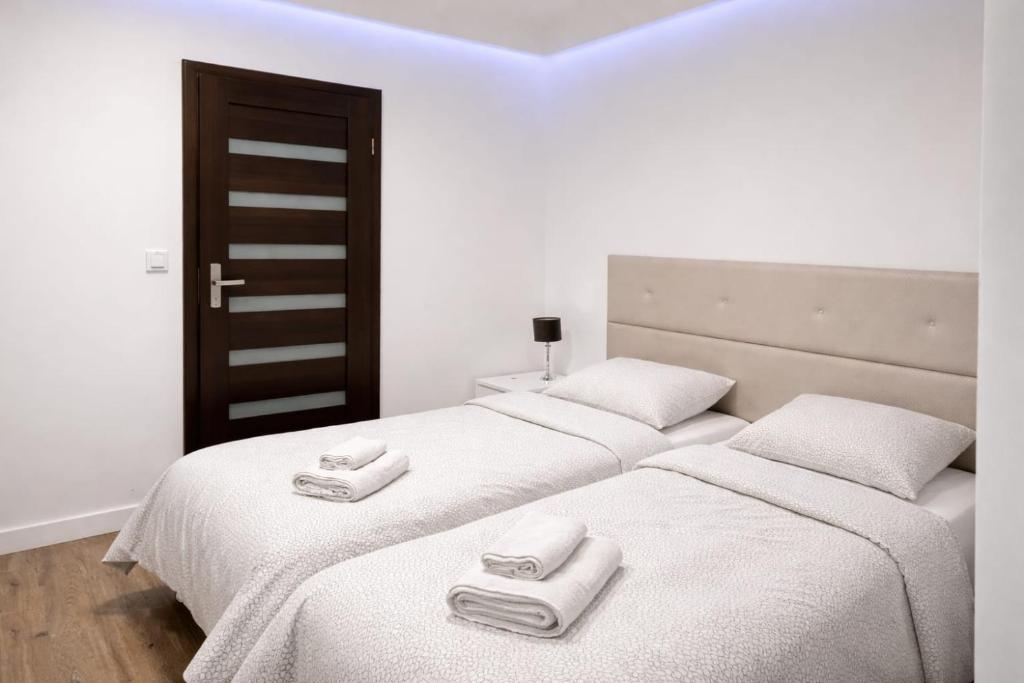 two beds in a room with white sheets and towels at Via Room in Raszyn