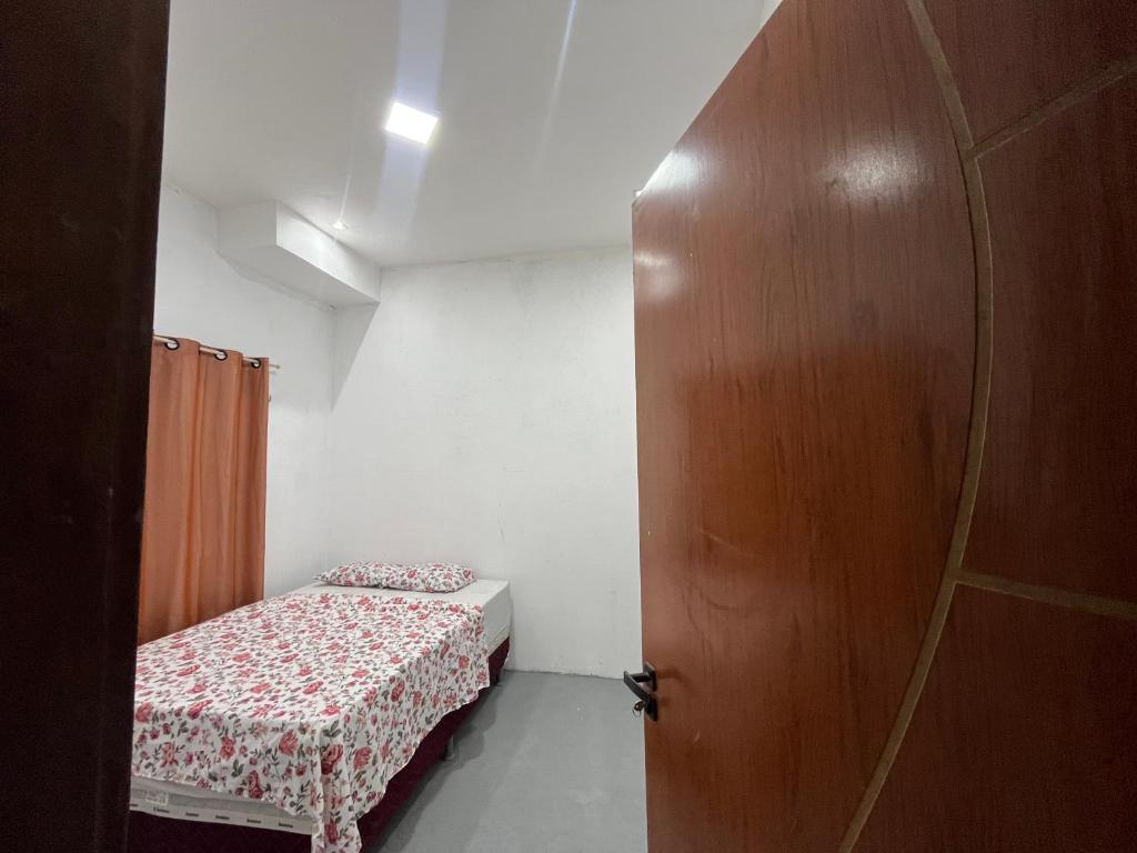 a small room with a bed and a wooden door at Residencial Lourenço - Vila Preá in Cruz
