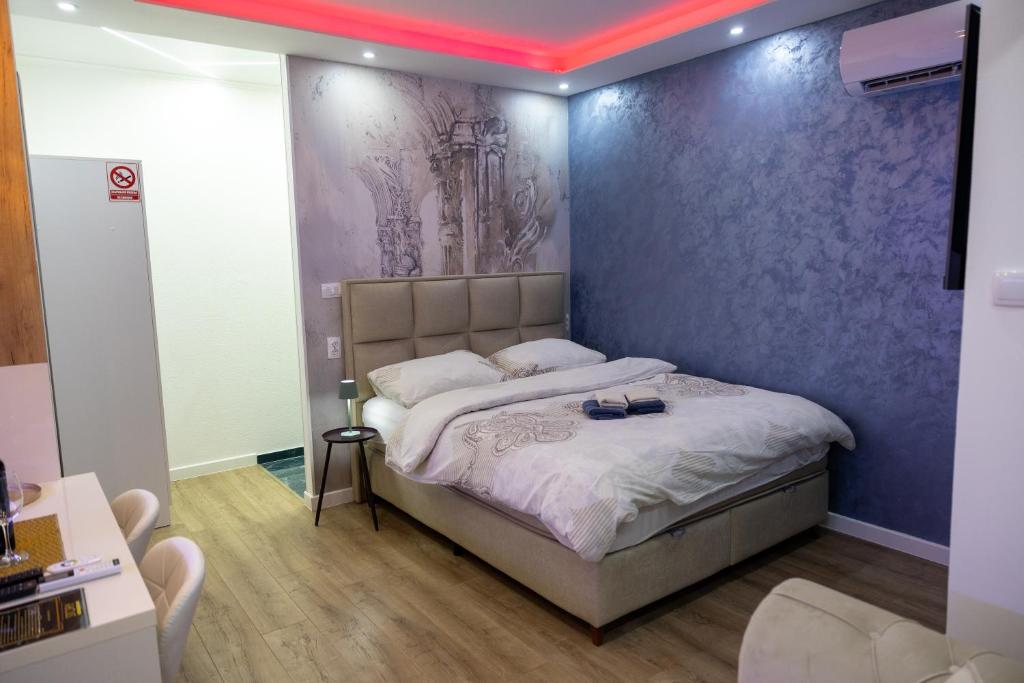 a bedroom with a bed with a purple wall at Foča Apartman STORY in Foča