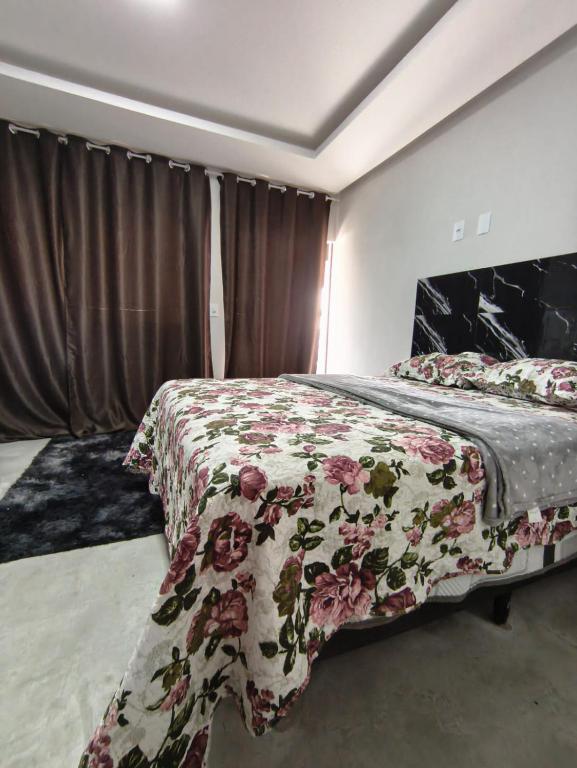 a bedroom with a bed with a floral bedspread at Lar Doce Lar Realizando Sono suíte1 in Arcos