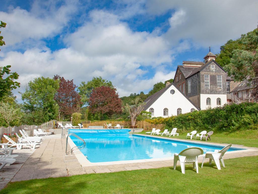 a pool with chairs and a house in the background at Tuckenhay, Clock Tower Cottage - Fjg in Ashsprington