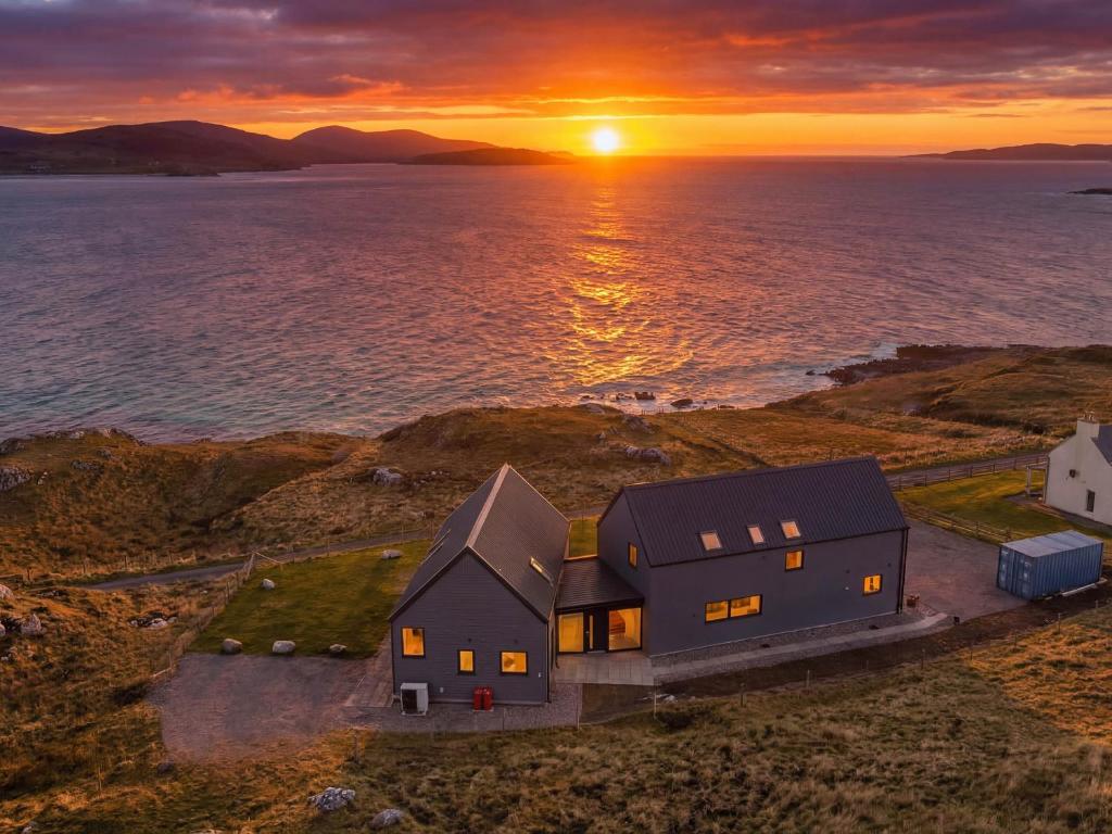 an aerial view of a house with the sun setting over the water at Taigh Rona in Tarbert
