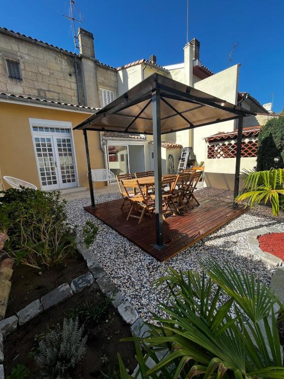 a wooden deck with a table and chairs under a pavilion at Maison de ville Libourne 3 chambres in Libourne