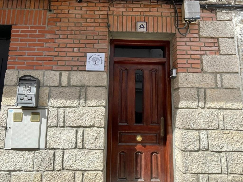 a brick building with a wooden door in front at Las raíces de los abuelos in Guadalix de la Sierra