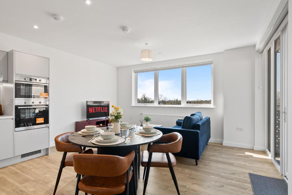 a kitchen and living room with a table and chairs at Luxury 2BR Staines 12 Mins to Heathrow & Thames in Staines