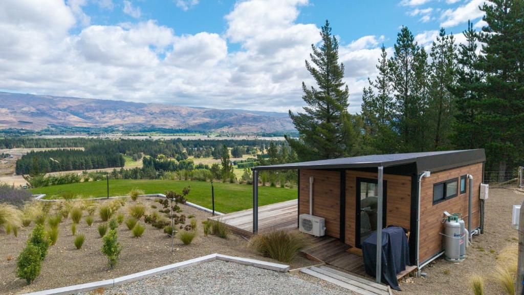 a small cabin with a black roof in a field at Modern studio overlooking Alexandra, Central Otago in Alexandra
