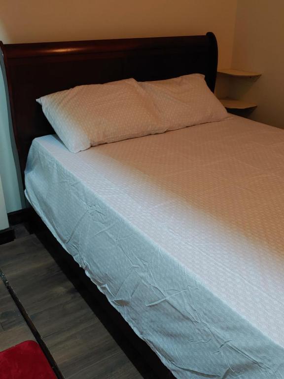 a bed with a wooden headboard and a white mattress at Vincy vybz in Kingstown