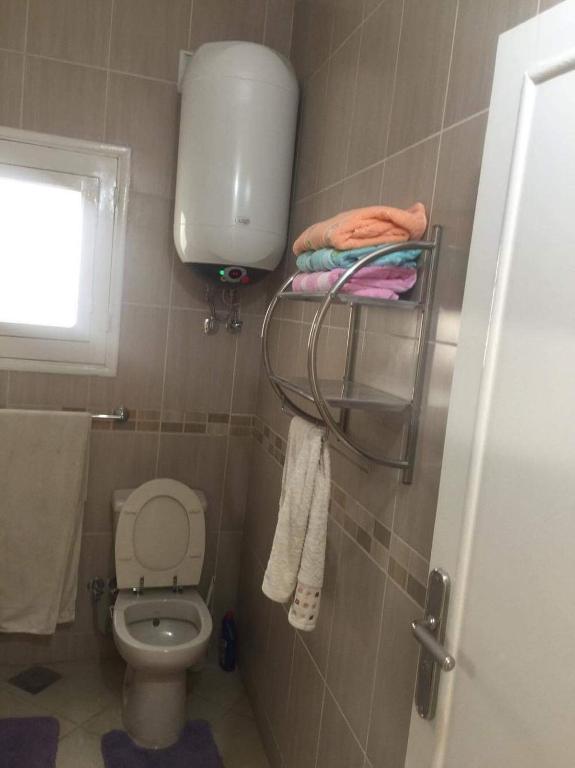 a bathroom with a toilet and a window and towels at Fatah Apartment 14 in Luxor