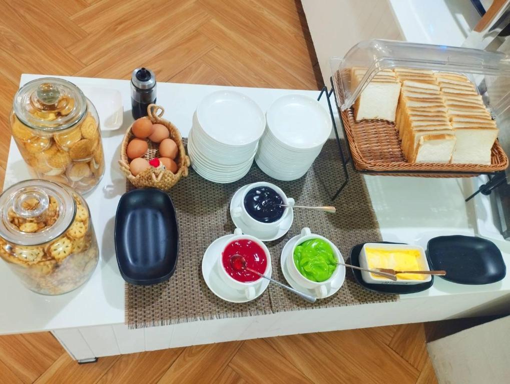 A breakfast table set with bread, pastries, eggs, spreads, fruit preserves and butter.