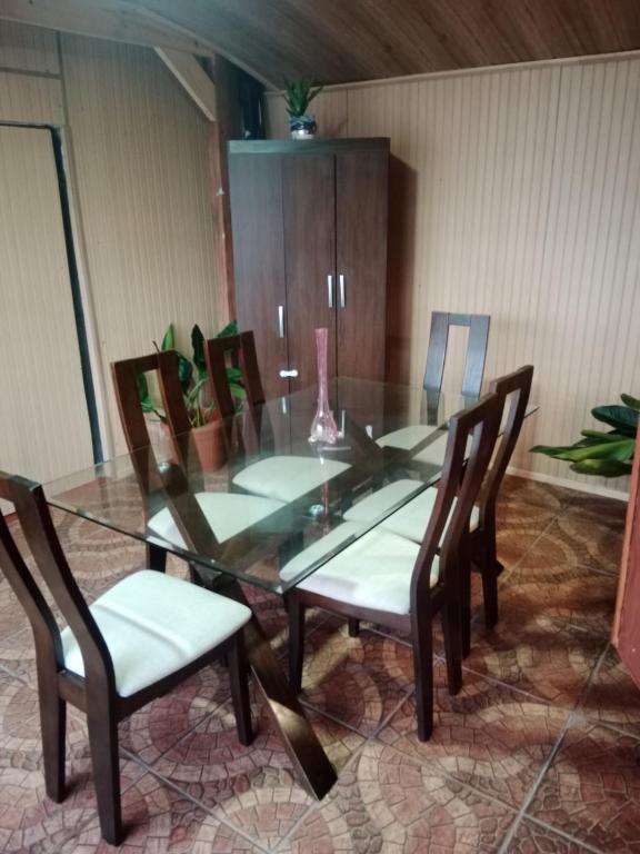 a glass dining room table with two chairs and a vase at Refugio Rancagua in Pueblo de Naturales