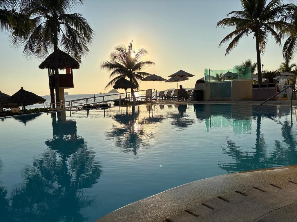 a swimming pool next to a beach with palm trees at Bay View Grand Ixtapa Exclusive in Ixtapa