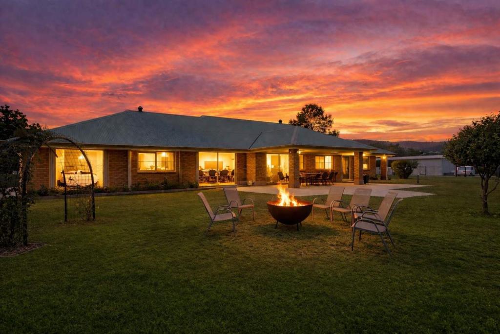 a fire pit in front of a house at sunset at Marignano Homestead in Broke
