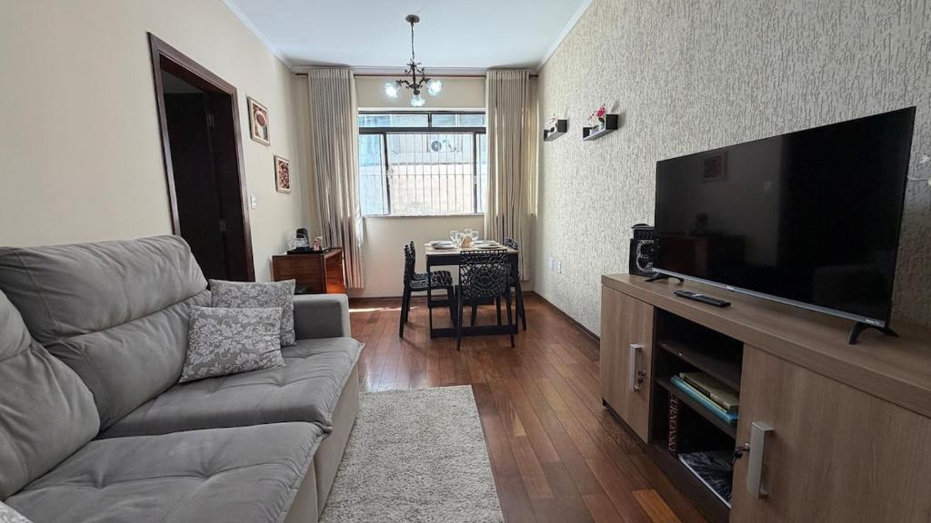a living room with a couch and a flat screen tv at Amplo apartamento completo no Centro Cambuí in Campinas