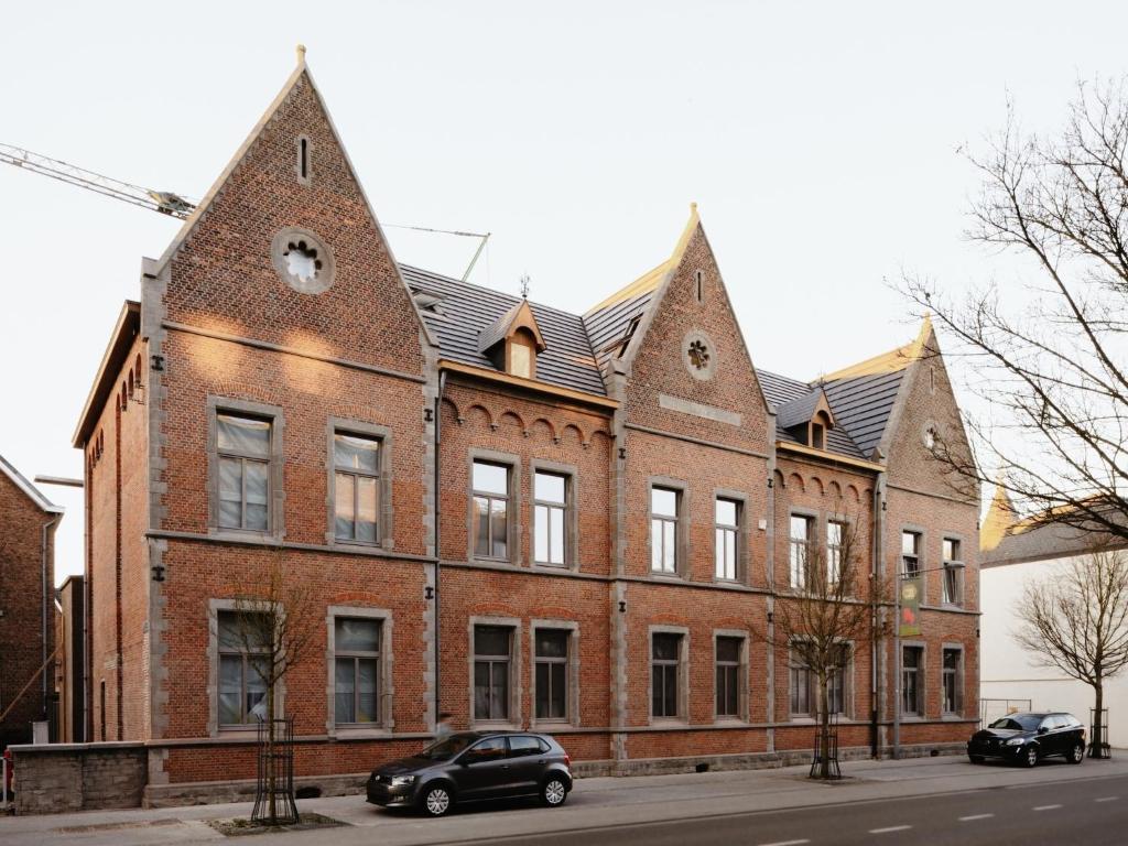 a large brick building with two cars parked in front of it at Charming ground-floor apartment in Bree in Bree