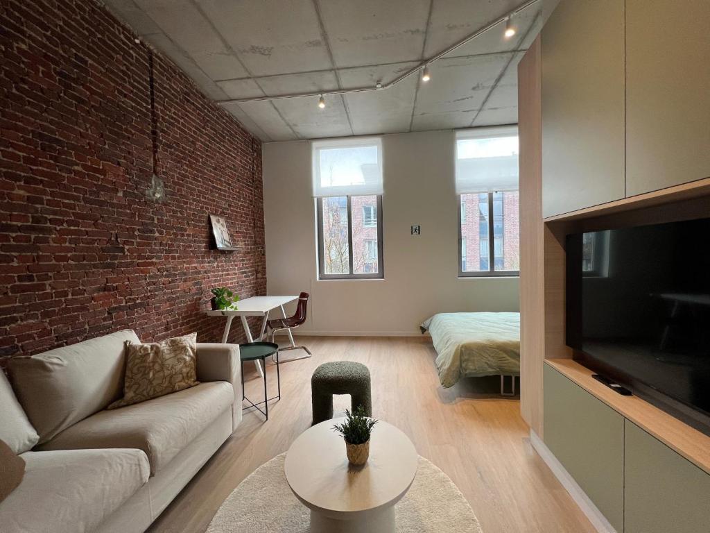 a living room with a couch and a brick wall at Attractive apartment in Bree for 2 guests in Bree