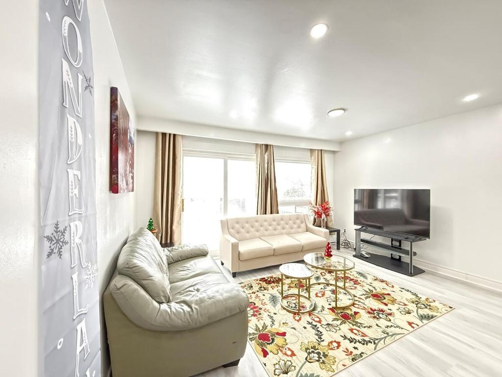 a living room with a couch and a television at Spacious 2 BR Suite with Parking, Backyard & Desk in Toronto
