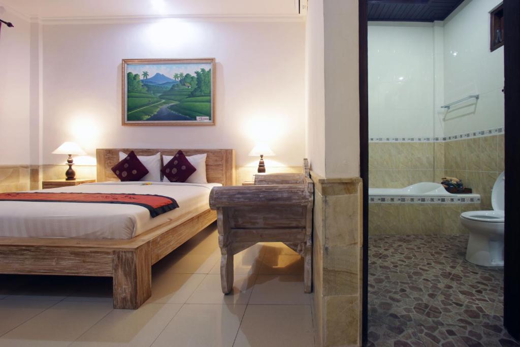 a bedroom with a bed and a bathroom with a toilet at Alam Terrace Cottages in Ubud